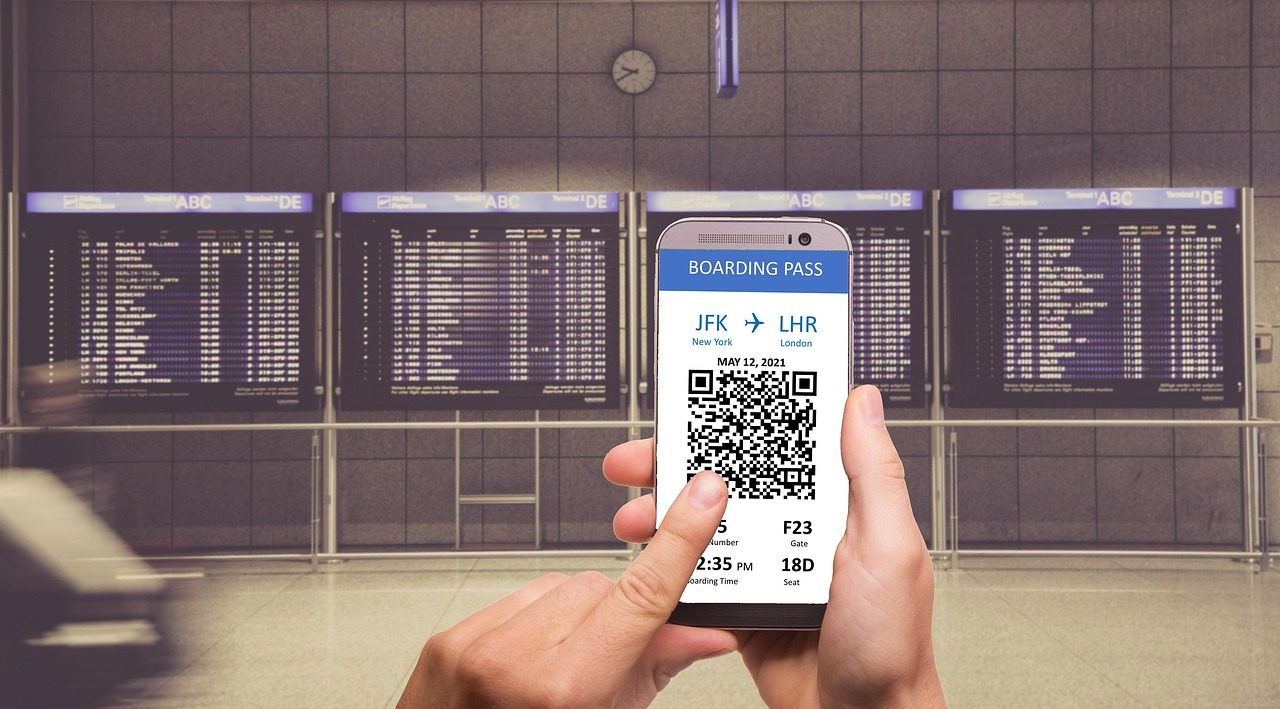 スマートフォンの搭乗券と発着案内 Digital boarding pass on a phone at the departures board